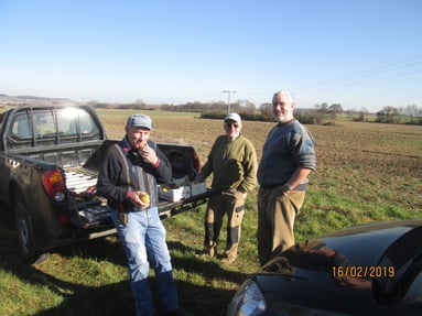 Gruppenbild am Pickup-Truck, ein Acker im Hintergrund
