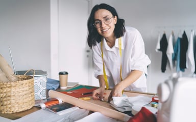 Junge Gründerin in ihrem Atelier, die Schnittmuster erstellt und an einem kreativen Designprojekt arbeitet