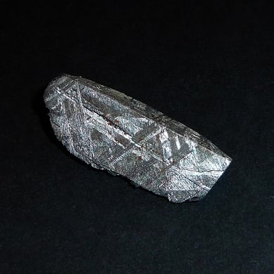 Ein kleines Stück des Gibeon-Eisen-Meteoriten (ca. 2,5 cm lang) mit schönen Widmanstätten-Strukturen und Neumannschen Linien