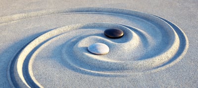 Yin Yang Zeichen im weissen Sand mit weissem und schwarzem Stein