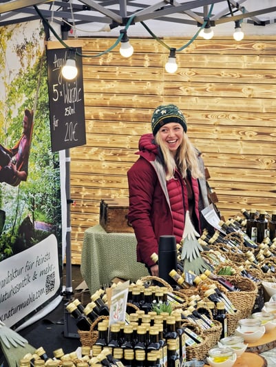 Geschäftsführerin Ann‑Kathrin Koch an einem Marktstand vor den Produkten der Mevlana Naturmühle.
