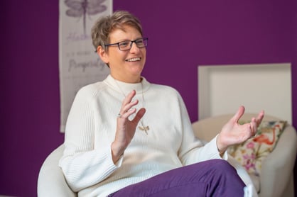 Katharina Wanha Psychologische Beraterin sitz in Beratungsraum und trägt weißen Pullover und violette Jeans