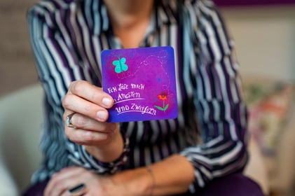 Katharina Wanha zeigt Karte mit dem Spruch Ich löse mich von meinen Ängsten und Zweifeln 