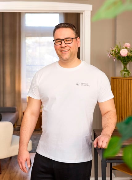 Das Bild zeigt einen Mann in einem weißen T-Shirt. Er trägt eine Brille.