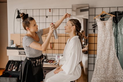 Brautstylistin macht Make-Up und Haarstyling für Braut
