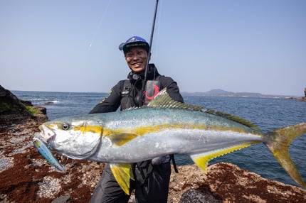 alt= "ジャンプライズのツーリミット ブルーバトルで釣り上げた10kg超のヒラマサと記念撮影する井上友樹"