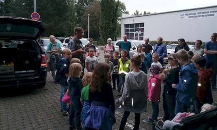 Gruppe von Kindern und Eltern auf einem Parkplatz