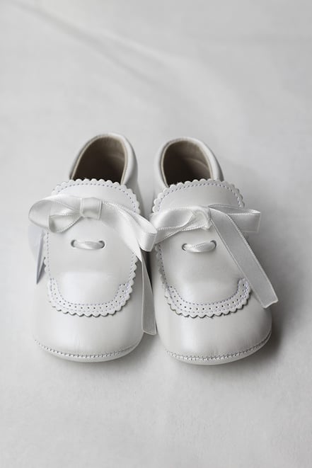Chaussons baptême bébé fille montants en cuir blanc cassé avec noeud en satin. Modèle chaussons cérémonie bébé Fil de Légende. Magasin vêtements baptême et cérémonie bébé Paris, Fil de Légende