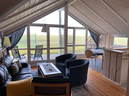 Wohnzimmerbereich mit dunklen Sitzmöbeln und hellen Holzwänden