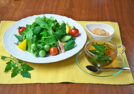 白い皿に盛り付けたベビーサラダミックスと納豆入りもろみ味噌ドレッシング。ハーブティーを添えて。