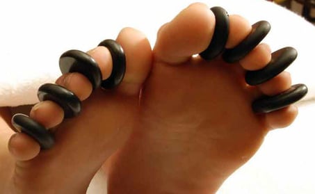 A massage photo of feet with hot stones  carefully and lovingly placed between their toes.