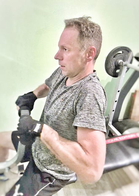 Ein Mann Mitte 40 trainiert mit Gewichten