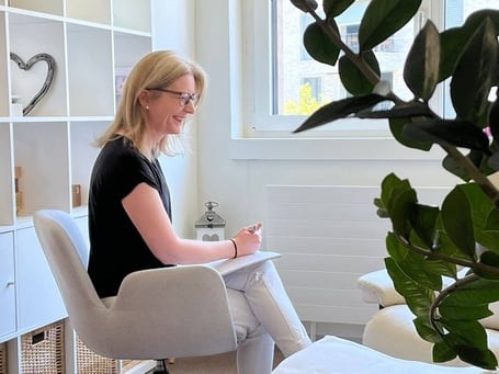 Mental Coach Karin Vogt mit Stift und Block, fröhlich lachend.