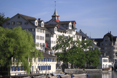 Häuserzeile der Zürcher Altstadt an der Limmat mit Flussbooten an der Boje