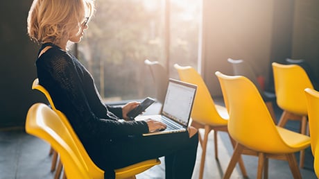 Teilnehmerin sitzt aufmerksam in Stuhlreihe bei einer Fortbildung