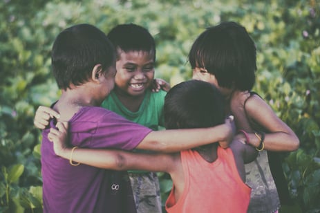 four kids hugging in a circle outside