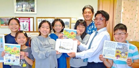 名護高校３年で防災士の宮城湊さん（右から２人目）から「はるかのひまわりの種」の寄贈を受けた松田小学校の児童会役員ら＝１２日、宜野座村立松田小学校