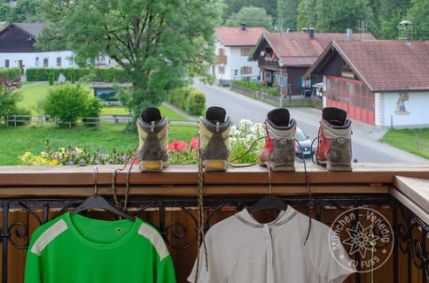 Wanderschuhe und Wanderbekleidung hängen zum Trocknen am Balkon
