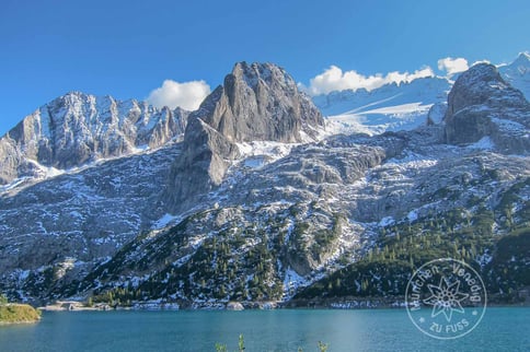 mit Schnee angezuckerte Berggipfel und im Vordergrund ein kristallklarer Bergsee