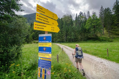 Wanderin passiert gelbe Wegweiser in Richtung Karwendelhaus