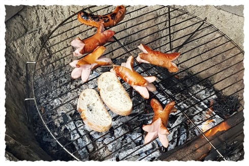 Servelats und Brot auf dem Rost der hofeigenen Feuerstelle