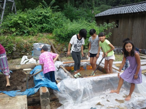 遊び感覚で、古民家で使う壁土をかき混ぜています。