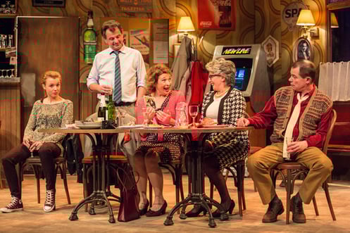 Les acteurs de la pièce sur scène dans le décor d'un café.