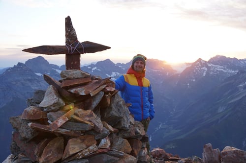 Bei Sonnenaufgang am steinernen Gipfelkreuz des Bristenstocks.