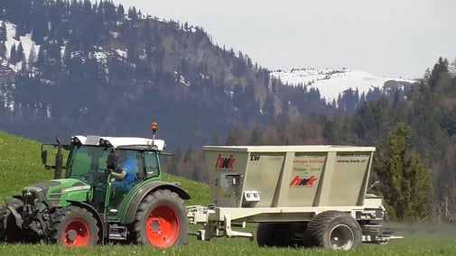 Bauer in einem Traktor, der gerade Steinsalz auf seinem Feld ausbringt