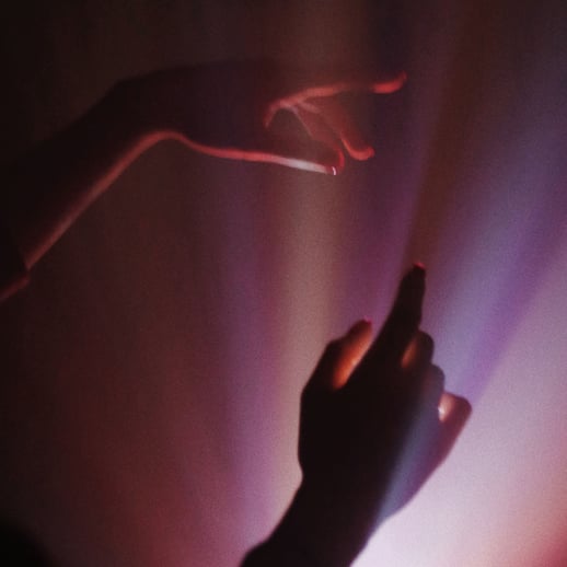 Zwei Hände schweben in pinken Lichtstrahlen.