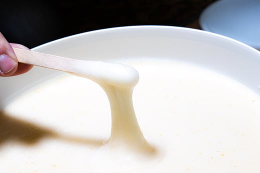 Miel de Trèfle Blanc de Nouvelle-Zélande avec texture crémeuse dans un seau de 10kg avec une touillette en bois et un aspect élastique et délicieux