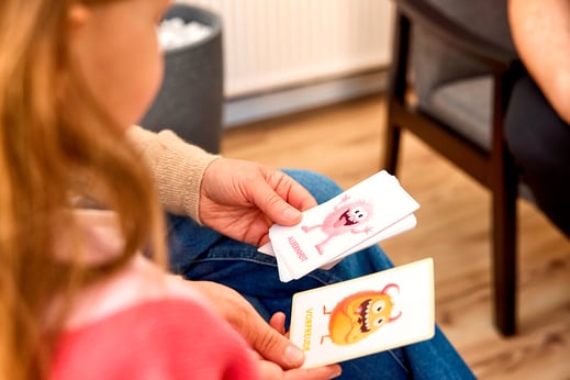 Das Bild zeigt ein Kind. Es schaut sich Gefühlskarten an.