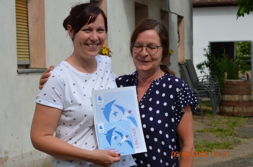 Frau Röck (links) und Frau Hoffmann (rechts) halten die Plakette "Schwalbenfreundliches Haus" zusammen mit der Urkunde