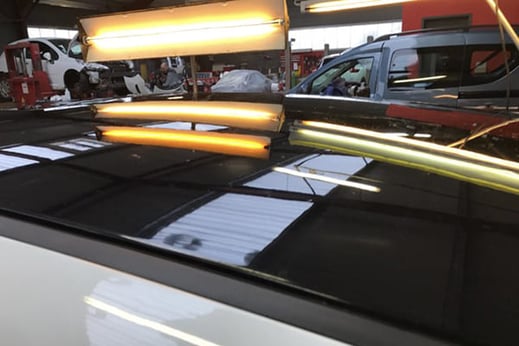 Toît de voiture grêlé noir éclairé par des néons spéciaux après réparation