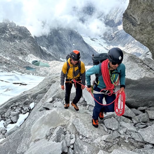 Bergführer sichert seinen Privatgast mit einem Seil während Aufstieg bei einer Hochtour in den Bergen 