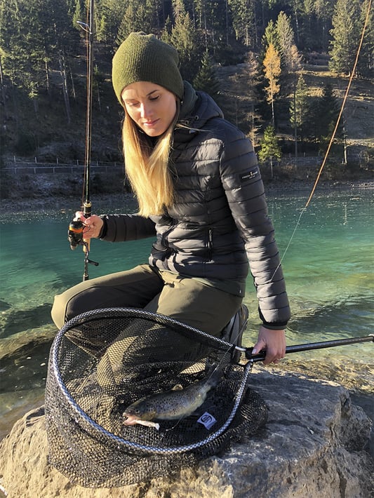 Impression Fischen am Bach - Fischerin zeigt in der Schweiz mit einem Wobbler gefangene Bachforelle.