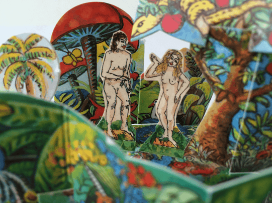 Foto eines Paradiesgärtchens mit Adam und Eva, beide nackt. Auch die Schlange ist zu sehen. Alle Figuren, Bäume und Büsche sind von Hand gezeichnet und bunt koloriert. auf dem Streichholzschachtel