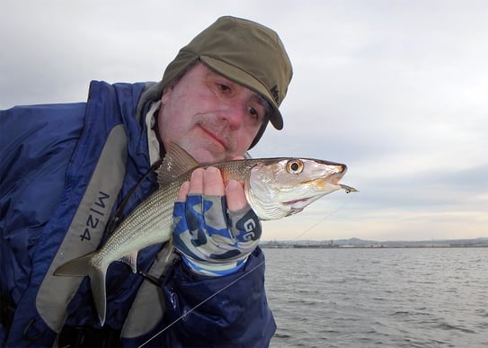 Angler with a winter bonefish caught fly fishing in San Diego Bay