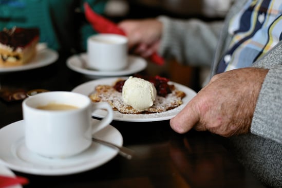 Symbolbild einer gedeckten Kaffeetafel: Auf einem Telle ist eine leckere Waffel mit einer Kugel Eis.