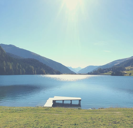 Ein glitzernder Bergsee mit Steg in der Sonne