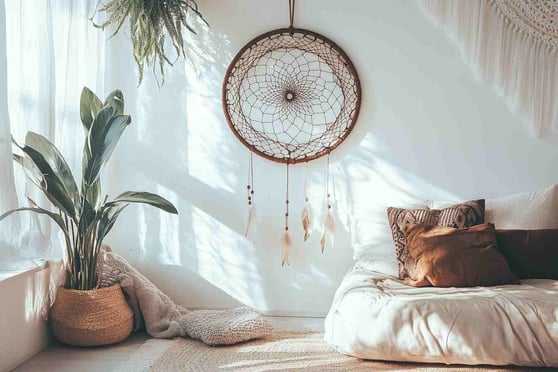 Boho-Schlafzimmer mit einem an der Wand hängenden Traumfänger, Inneneinrichtung eines modernen Hauses im Bohème-Stil, natürliches Licht aus dem Fenster, weiße Wände mit sanften Schatten und