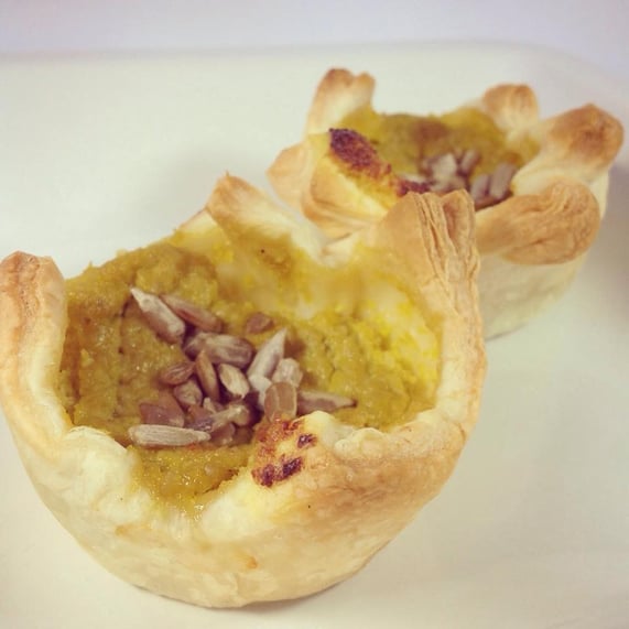 Blätterteig-Quiches gefüllt mit gelbem, mildem Paprika-Pesto, dekoriert mit Sonnenblumenkernen.