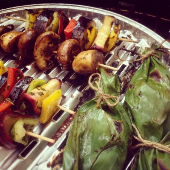 Gefüllte Bananenblätter auf dem heißen Grill in bester Gemüsegesellschaft.