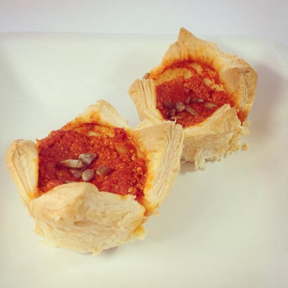 Blätterteig-Quiches gefüllt mit Paprika-Chili-Pesto, dekoriert mit Sonnenblumenkernen.