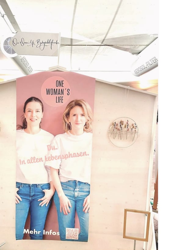 Großes Roll-up mit Markenbotschaft von One Woman’s Life am Messestand – Teil des visuellen Auftritts und der Messegestaltung