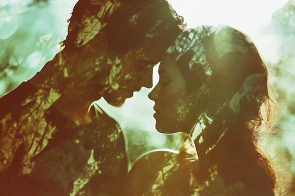 Eine Doppelbelichtung eines Fantasy-Liebespaares, das sich im Wald küsst, mit Weichzeichnerfotografie, Silhouetten, einem romantischen Kern, natürlichem Licht, Grüntönen und einer verträumten Atmosphäre.