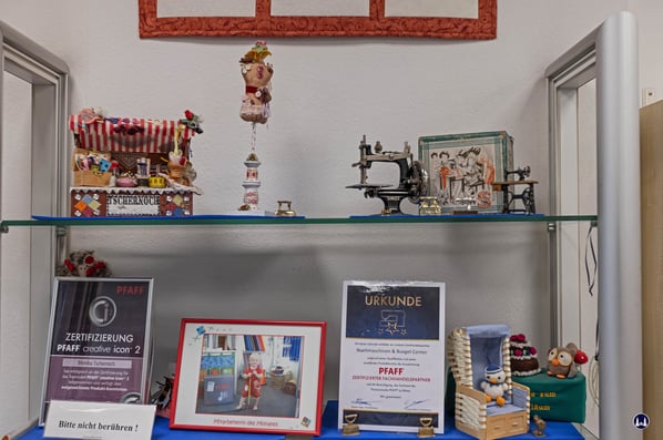 Zertifikate, die Monika Tschernoch bei Lehrgängen der Fa. Pfaff erhalten hat inmitten von Dekorationsartikeln.