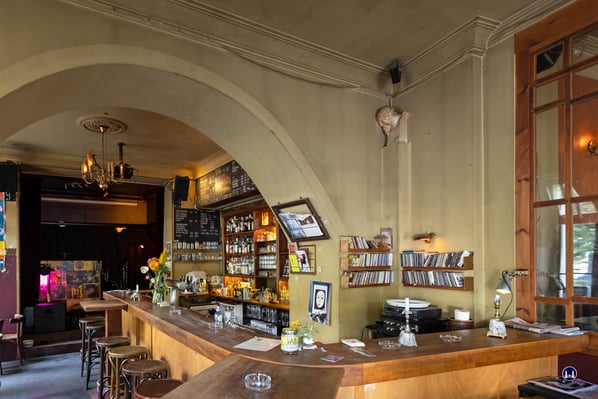 Die dem Eingang gegenüberliegende Bar. Rechts die gläserne Trennwand zum "oberen" Gastraum, links im Hintergrund die Bühne des WATT, auf der eine Vielzahl an bekannten und weniger bekannten Musikern, Bands und Künstler auftraten. 