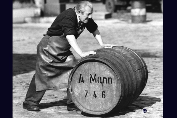 Ein Mitarbeiter der Spedition imitiert das Firmensymbol: Den Fassroller.