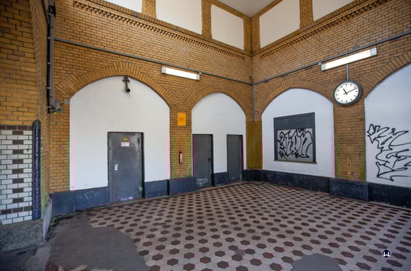 Die dem Eingang gegenüberliegende Seite der Halle. Hinter den vier heute weitgehend zugemauerten Bögen befand sich die für den Bahnhofsbetrieb damals notwendigen Funktionsräume. 